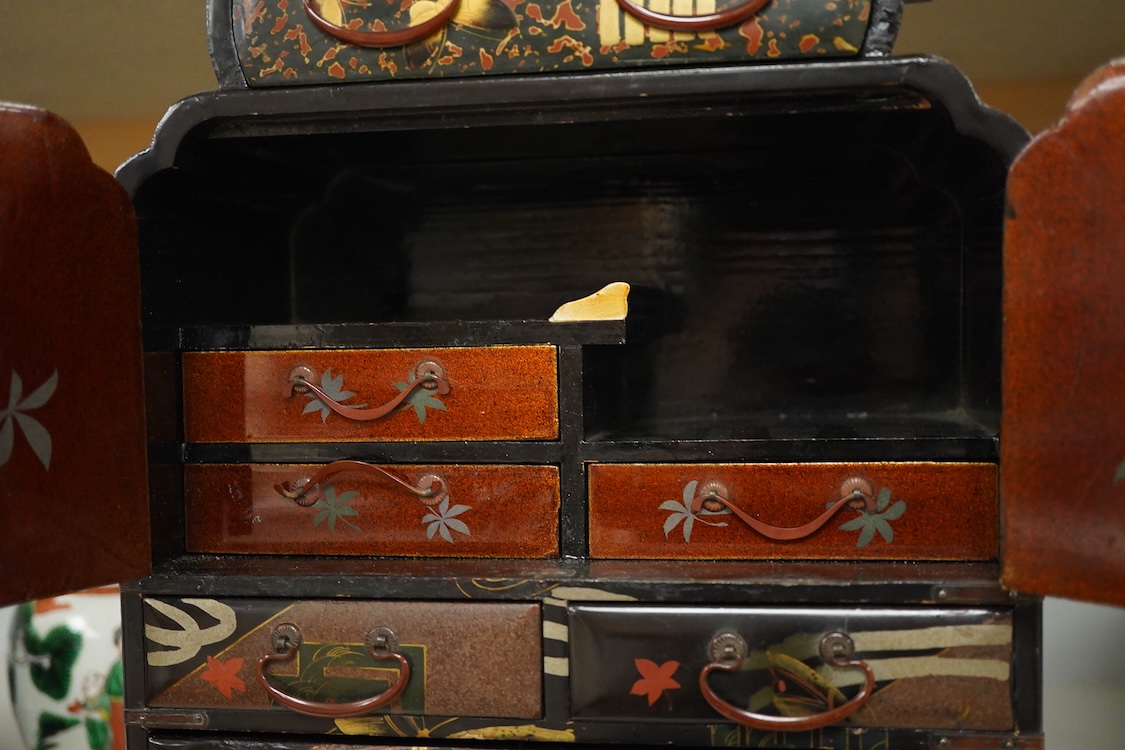 A Japanese gilt decorated black lacquer table cabinet, fitted with seven drawers, with key, 35cm high